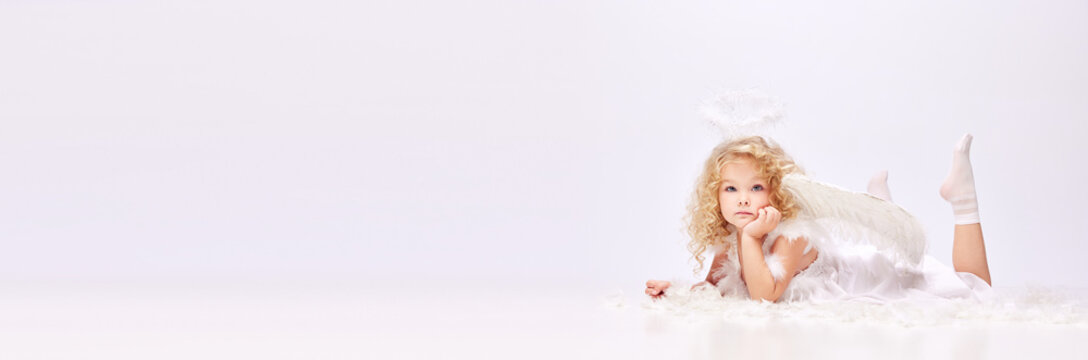 Dreams. Tender, cute little baby girl, child in image of angel isolated over white studio background. Concept of childhood, imagination, fantasy, fashion and beauty, holidays. Banner