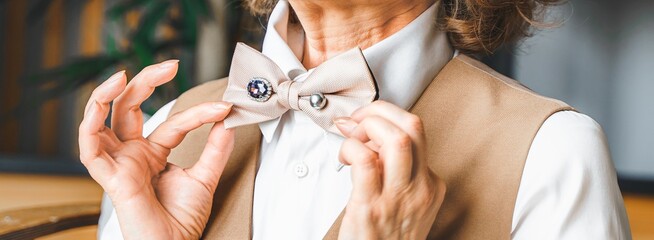 Confident stylish mature middle aged elderly business woman in suit, white shirt, bow tie pin with...