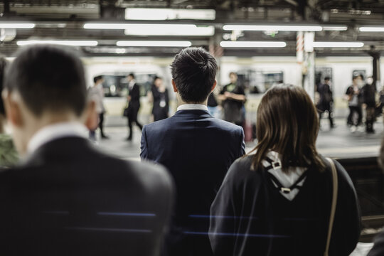 Passengers traveling by Tokyo metro. Business people commuting to work by public transport in rush hour. Shallow depth of field photo.