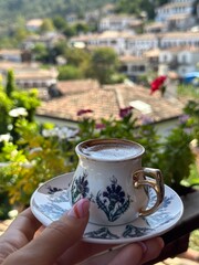 turkish coffee in a traditional porcelain mug and cute village at the background