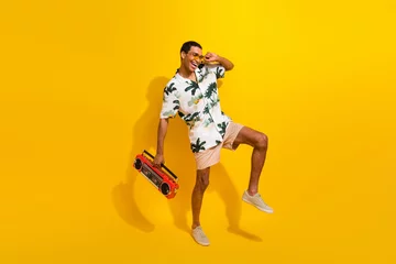 Tuinposter Full size photo of handsome young guy dancing have fun boom box dressed stylish palms print outfit isolated on yellow color background © deagreez