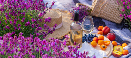 wine, fruits, berries, cheese, glasses picnic in lavender field Selective focus