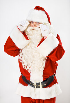Santa claus, playful and portrait in studio for Christmas holiday, festive season or celebration. Male person, red outfit and glasses as white background mockup for greeting, vacation or winter break