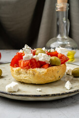 Delicious Cretan appetizer dakos with tomatoes, feta cheese and olive oil, vertical photo. Greek cuisine. Close-up.