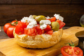 Greek dish Dakos with fresh tomatoes and feta cheese on a wooden table. Close-up.