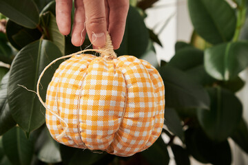 Handmade orange white plaid pumpkin crafted from checkered fabric, a charming symbol for both Thanksgiving and Halloween celebrations, adding warmth and DIY spirit.