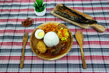 Red spiced chicken rice with pickled cucumber and carrots, boiled egg, potato fritters, sweet spiced fried potatoes and fish sauce.