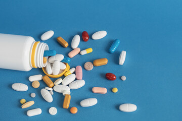 Pills scattered on a blue background. Medicines are scattered on the table. Close-up, copy space. Healthcare and treatment concept