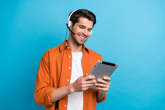 Photo of cute smiling man dressed orange shirt working client support modern device isolated blue color background