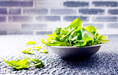 Fresh baby spinach leaves in bowl on stone background