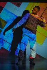 african american man standing and gesturing with hands in digital projector lights, fashion concept