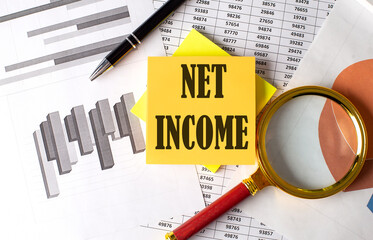 NET INCOME text on a sticky on red notebook on chart background