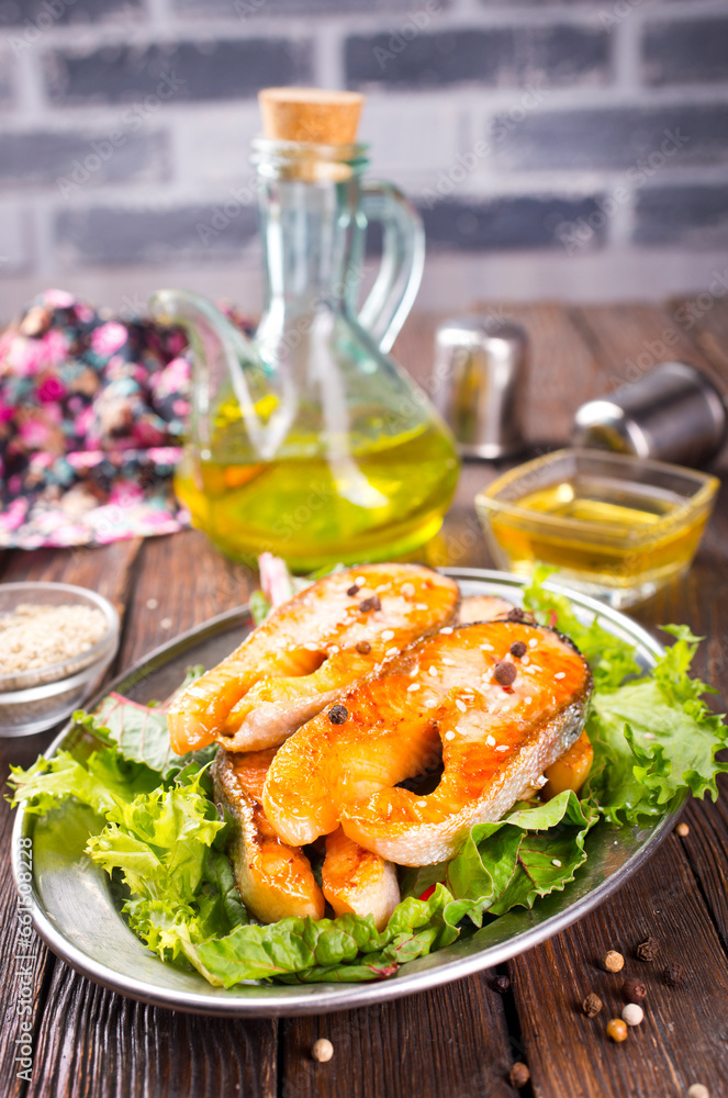 Wall mural fried salmon steak with spice and vegetables on wooden table