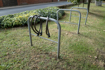 Trio of heavy duty bike chains seen attached to one of three metal bike racks located outside an...