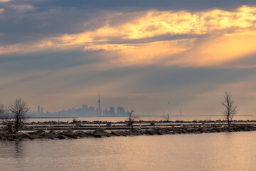 Dramatic moody sunrise light with sun rays over Lake Ontatio with the Toronto skyline in the background. Port Credit, Mississauga