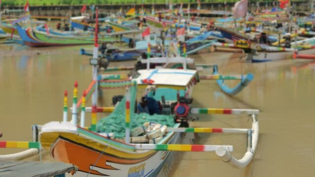 Wooden fishing boats are densely parked in a harbor at noon on the coast of Java, Indonesia. Depicts the difficulty of traditional fishermen getting fish and losing their jobs