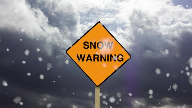 A simulated Snow Warning yellow diamond road sign with timelapse dark clouds and falling snow flakes.