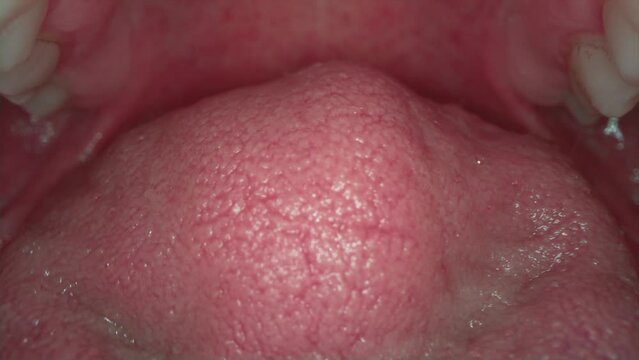 Real video of human tongue. Macro frame inside the mouth. Teeth and jaw, soft tissues of the cheeks. Tongue surfaces, taste buds.