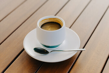 Cup of black coffee on a wooden table in a cafe.