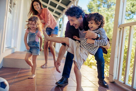 Young family kicking a soccer ball on the balcony of their home