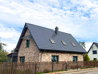 Elegant single family house in Poland seen from the street, fence and roof as main features. Dutch style bricks exterior.