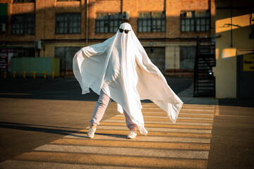 Celebrating halloween. Ghost Challenge 2021. A man dressed as a ghost from a sheet and sunglasses...