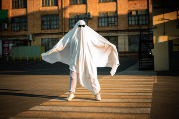 Celebrating halloween. Ghost Challenge 2021. A man dressed as a ghost from a sheet and sunglasses...