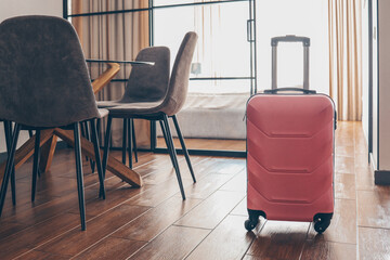 Pink suitcase in light hotel room