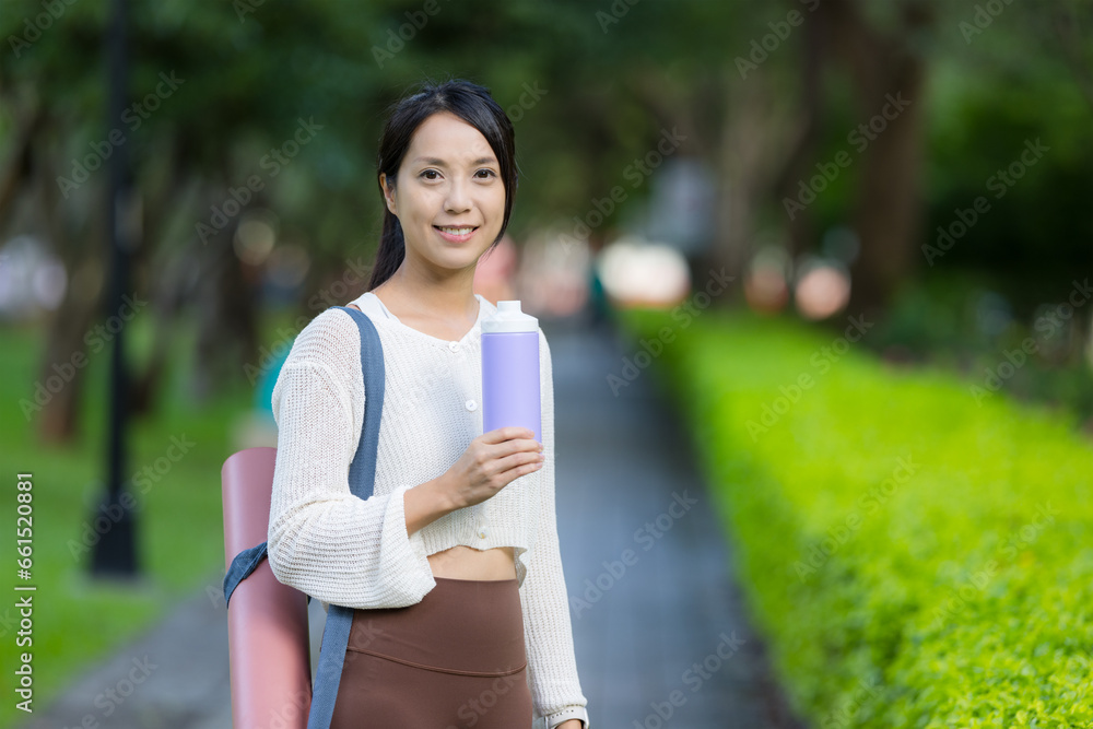 Wall mural woman bring her yoga mat and water bottle at park