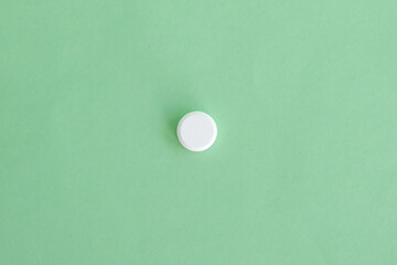 Close up a white pill on green background. Medical health care pharmacy concept background. Selective focus included. Open space area.