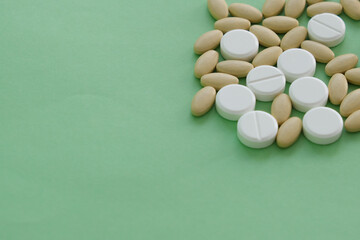 Close up top view heap of pills vitamin supplement on green background. Medical health care pharmacy concept background. Open space area.