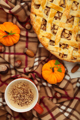 Apple pie and coffee with autumn decoration on blanket.