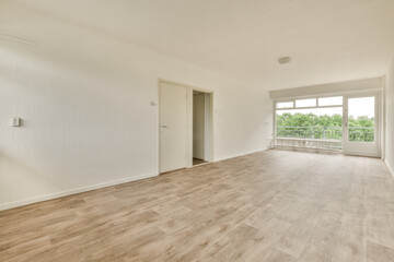 an empty living room with wood flooring and white paint on the walls there is a large window in the corner
