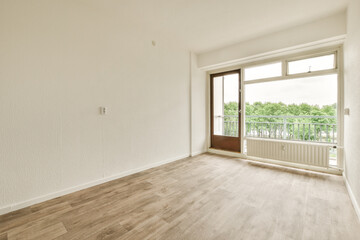 an empty room with white walls and wood flooring, looking out onto the balcony from the living room door