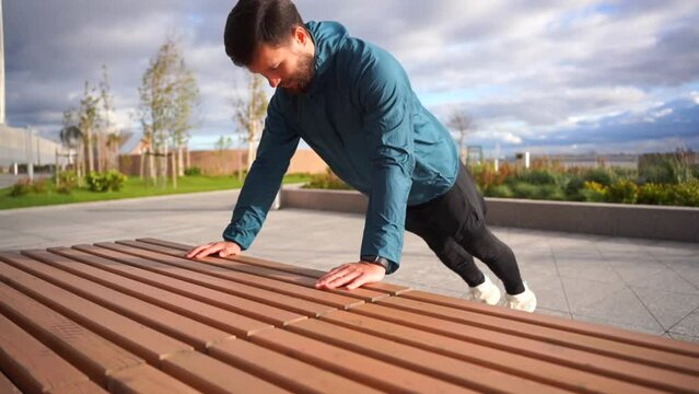 A male sports athlete trains push-ups to develop pectoral muscles. Motivation and fitness exercises. Slow motion video.