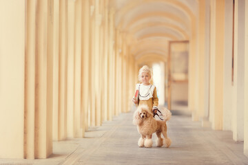 Little girl in beautiful yellow retro dress with poodle 