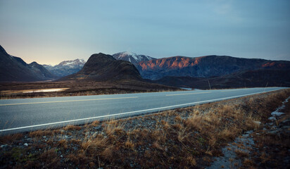 View of a road on high altitude leading through the norweigian mountains at sunset.