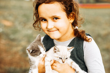 Adorable little girl holding kittens cats outdoor in nature. Pet concept.