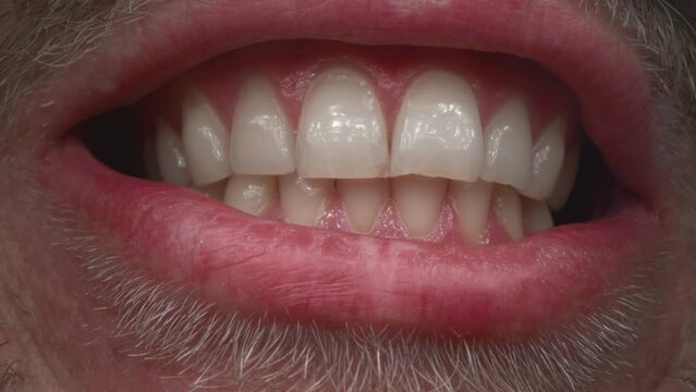 White big clean teeth of a man. The guy shows his jaw, smiles beautifully. Oral care. Open your mouth wide. Close up of teeth isolated. Detail of a smile bearded man.
