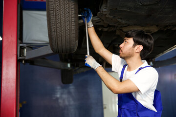 mechanic using ratchet wrench and fixing underneath the car