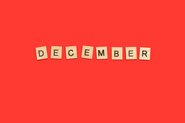 Bloques de madera formando la palabra December sobre un fondo rojo liso y aislado. Vista superior. Copy space