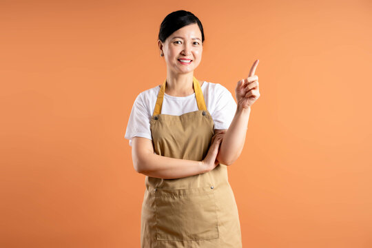 Portrait of Asian female housewife posing on brown background