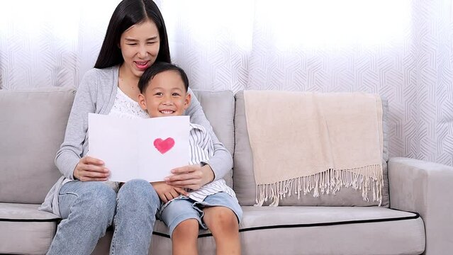 Lovely single mom getting present from kid happy mom enjoy reading handmade love card from small son cheerful embrace little child on mother day, valentine or birthday Love and care in family