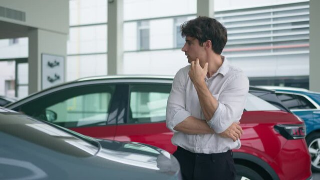 Pensive thoughtful customer Caucasian man client buyer male businessman guy thinking looking at car choosing new modern luxury vehicle in automobile salon store choose auto for rent transport buying