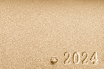 Fototapeta na wymiar Imprints of numbers 2024 new year and a shell left side on a golden sand
