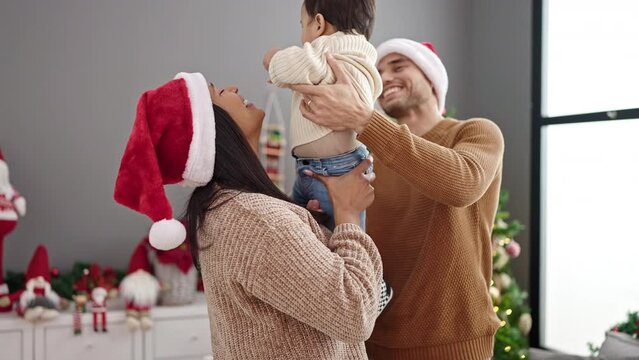 Couple and son hugging each other standing by christmas tree at home