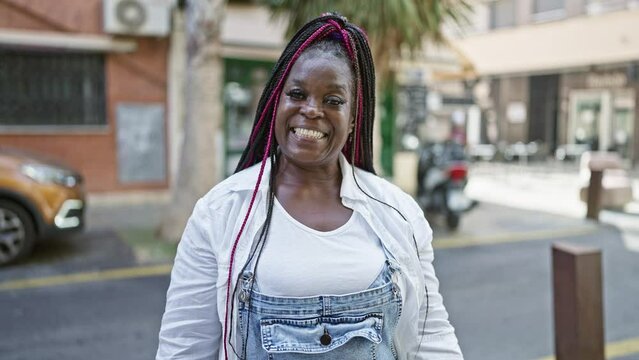 Beautiful african american woman exuding confidence, cheerfully laughing and enjoying life while casually standing on an urban city street, beaming with positivity and joy.