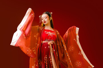 Beautiful Asian woman with clean fresh skin wearing cheongsam qipao posing on red background....