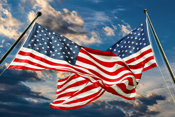 Two American flags on bright sky with clouds