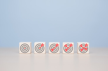 Business target goal progress tracking. Dartboard with many arrow icons on wooden blocks for...